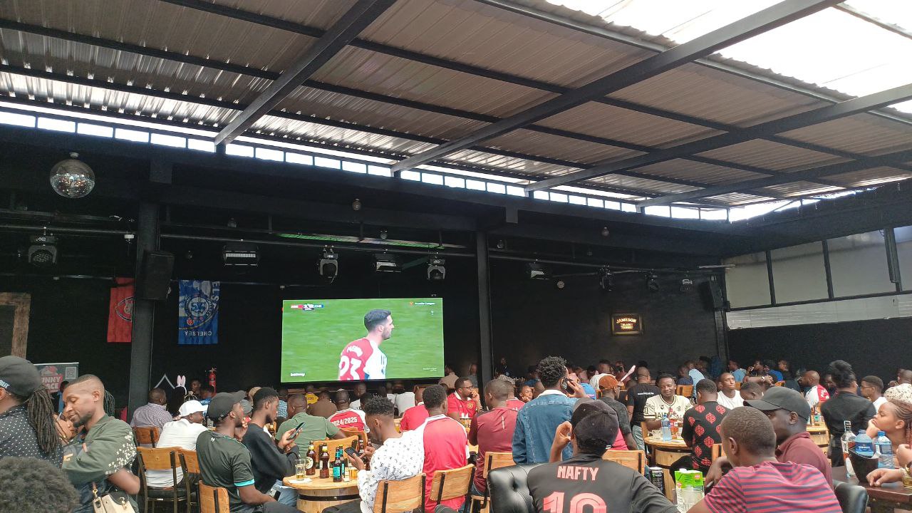 football-fans-watching-match-on-big-screen-at-bar